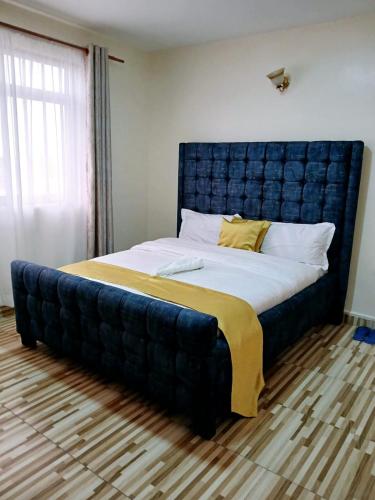 a large bed with a blue headboard in a room at Kitengela two bedroom stays in Kitengela 