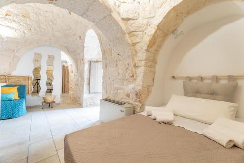 a bedroom with a bed and a stone wall at Trullo Aia Antica in Ceglie Messapica