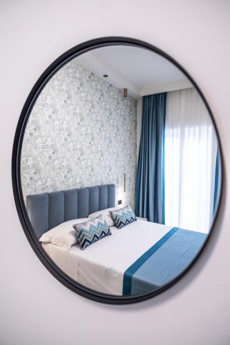 a mirror reflecting a bed in a bedroom at Ambrosia Room & Apartment in Rossano