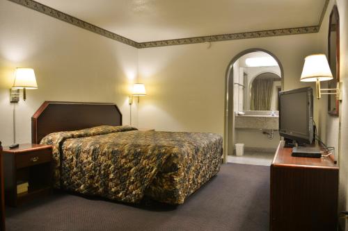 a hotel room with a bed and a flat screen tv at The Flamingo Motel San Jose in San Jose