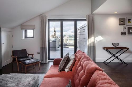 a living room with a red couch and a window at Old Town Chambers, Autograph Collection in Edinburgh