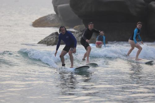 three people riding a wave on surfboards in the water at Star Rest Beach Hotel in Arugam Bay