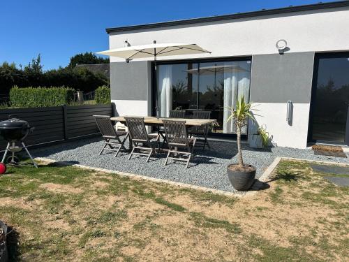 a patio with a table and chairs and an umbrella at Gîtes Rozanna avec accès détente SPA JACUZZI in Saint-Jean-de-la-Rivière
