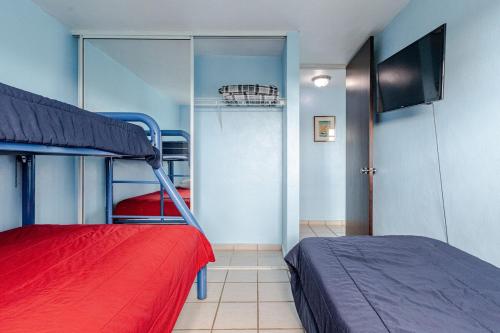 a bedroom with two bunk beds and a flat screen tv at Costa Brava Beach & Pool Apartment 24-402 in Ceiba