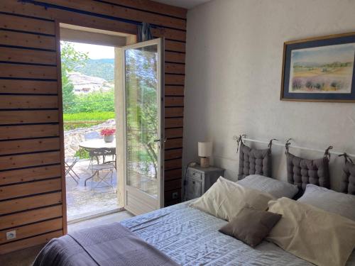 a bedroom with a bed and a sliding glass door at Le Mas de la Roche in Montbrison-sur-Lez