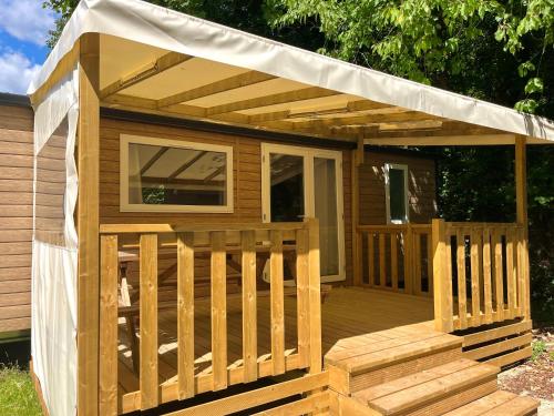 a wooden deck with a pergola on it at Mobil-home 3 chambres Premium - Camping la Faloise in Angicourt