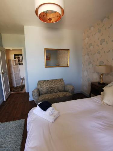 a bedroom with a white bed and a chair at Maison la tour in Néré