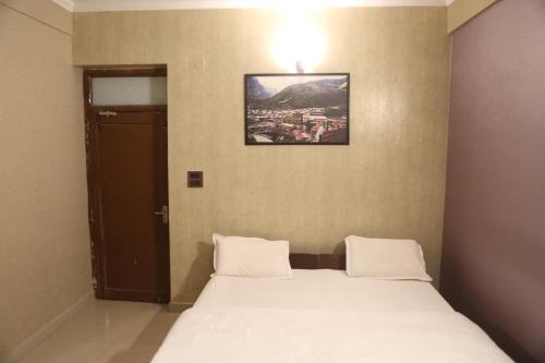 a bedroom with a bed with a picture on the wall at Vedic Dham Ganga in Rishīkesh