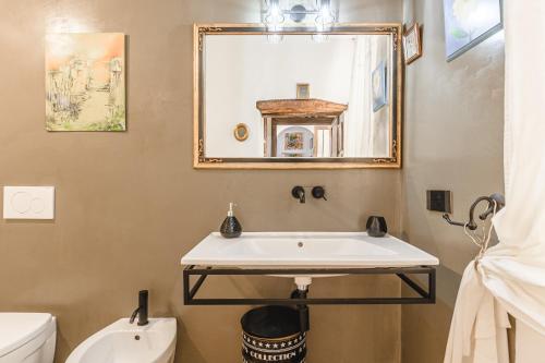 a bathroom with a sink and a toilet and a mirror at La Casa del Pozzo in Trequanda