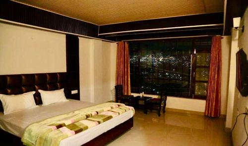 a bedroom with a large bed and a large window at Hotel SHIMLA REGENCY CHAKKAR in Shimla