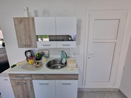 a white kitchen with a sink and a door at Apartmani Velić in Bugojno