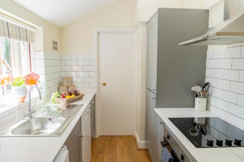 a white kitchen with a sink and a window at Historic 2 bed gatehouse in private parkland in Brockenhurst