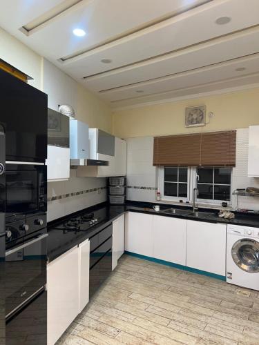 a large kitchen with white cabinets and black appliances at 1-Room Cozy Private Stay in Changla Gali in Abbottābād