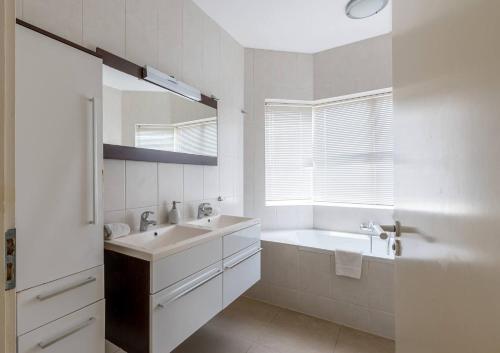 a bathroom with a sink and a tub and a mirror at Blue Bay Ocean Dreams Beachfront in Sint Michiel