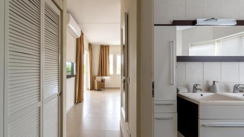 a white kitchen with a sink and a hallway at Blue Bay Ocean Dreams Beachfront in Sint Michiel