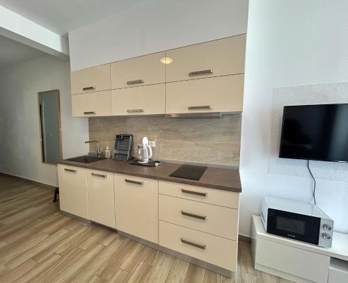 a kitchen with white cabinets and a flat screen tv at Flabelline in Bar