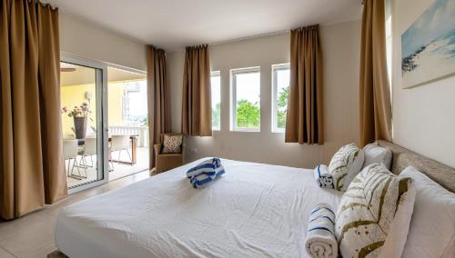 a bedroom with a large white bed and a balcony at Blue Bay Ocean Dreams Beachfront in Sint Michiel