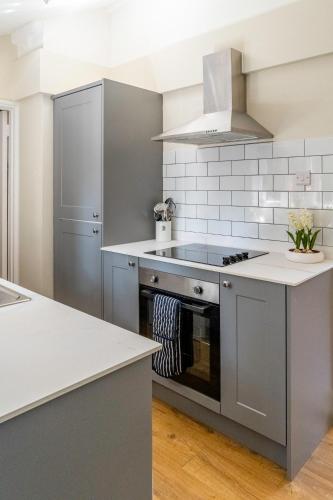 a kitchen with gray cabinets and a stove at Historic 2 bed gatehouse in private parkland in Brockenhurst