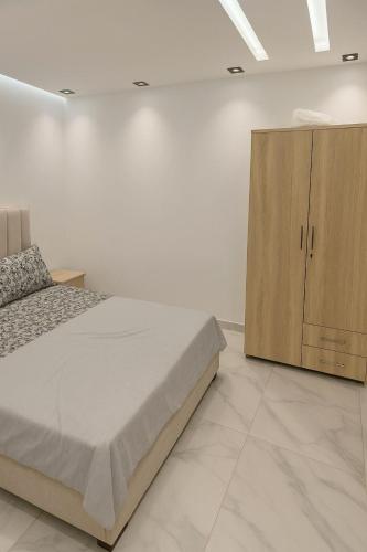 a bedroom with a bed and a wooden cabinet at CHU -Family Apartment in Tangier in Daidatz