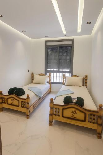 two twin beds in a room with a window at CHU -Family Apartment in Tangier in Daidatz