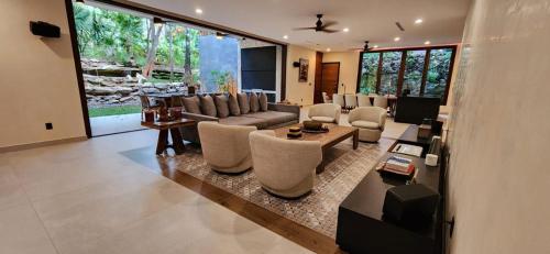 Una sala de estar con un sofá y sillas y una mesa. en Spacious and luxurious villa with 4 bedrooms, swimming pool, tennis court, and beach within walking distance, en Playa del Carmen