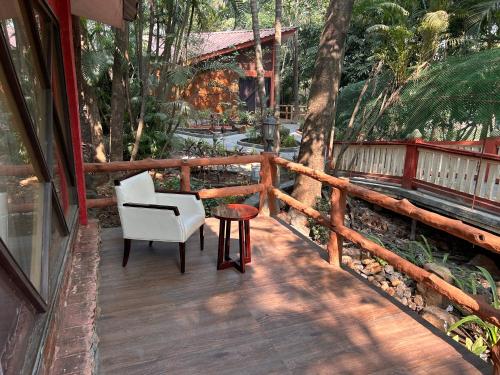a wooden deck with a chair and a table on it at Aayush Resort in Kālundri
