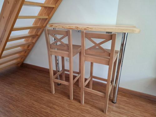 a wooden table and two stools next to a staircase at Apartamenty Młyn in Męcikał