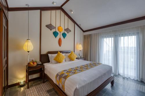 a bedroom with a large bed and a large window at Cozy Savvy Hoi An - The Quintessence of Exquisite Retreat in Hoi An
