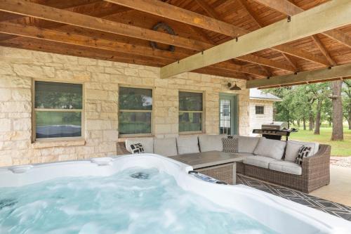 a hot tub in a patio with a couch and a table at Pecan Farm Haus in Fredericksburg