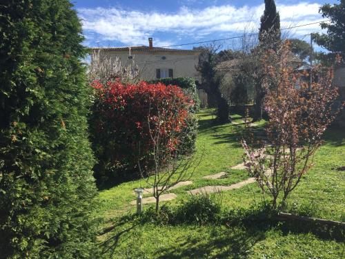 a garden with red bushes and a house at Le Mas de la Roche in Montbrison-sur-Lez