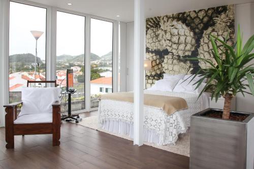 um quarto com uma cama e uma parede de janelas em Casa Senhora da Rosa em Ponta Delgada