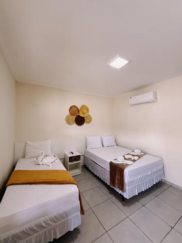 a bedroom with two beds and a clock on the wall at Village Comfort Hotel in Canindé de São Francisco