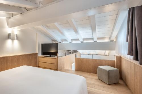 a bedroom with a white bed and a television at Hotel Lajadira & Spa in Cortina dʼAmpezzo