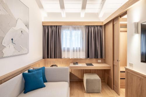 a hotel room with a desk and a couch at Hotel Lajadira & Spa in Cortina dʼAmpezzo