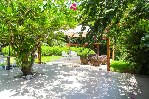 a garden with a tree and some pink flowers at Boutique Hotel Particulier in Abidjan