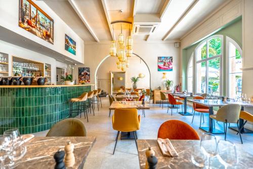 a restaurant with tables and chairs and windows at Hotel Les Palmiers in Sainte-Maxime