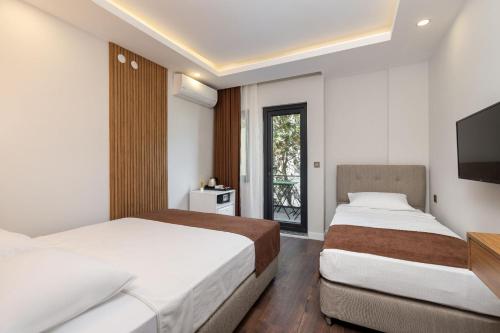 a bedroom with two beds and a tv and a window at Royal Dream's Hotel in Kemer