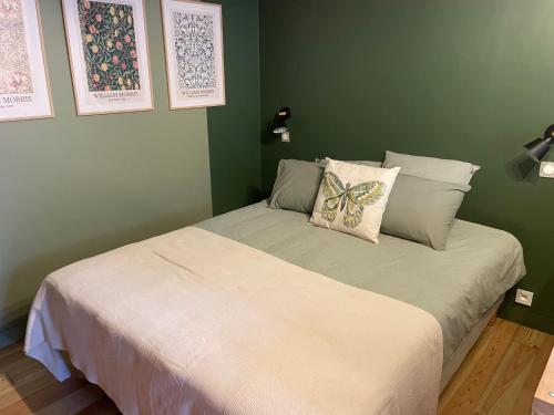a green bedroom with a bed with a butterfly pillow at Les ptis chiffons in Lacanau