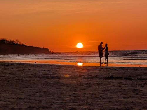 a couple standing on the beach watching the sunset at Seis Playas Hotel in Tamarindo