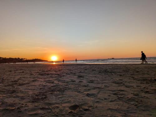 a group of people walking on the beach at sunset at Seis Playas Hotel in Tamarindo