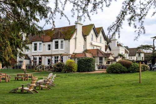 a large white house with tables and chairs in the grass at Worplesdon Place Hotel in Guildford