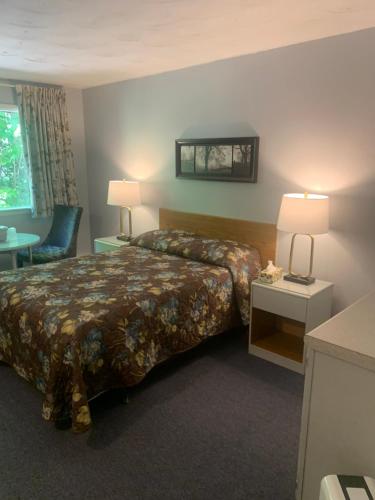 a hotel room with a bed and a table at Skyline Motel in Fredericton