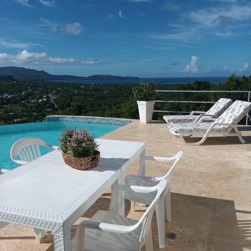 a white table and chairs next to a swimming pool at Apartamento panorámico vista al mar in Las Galeras