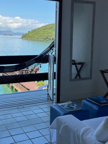 a room with a view of the water and a hammock at Pousada Casa do Bicho Preguiça in Angra dos Reis
