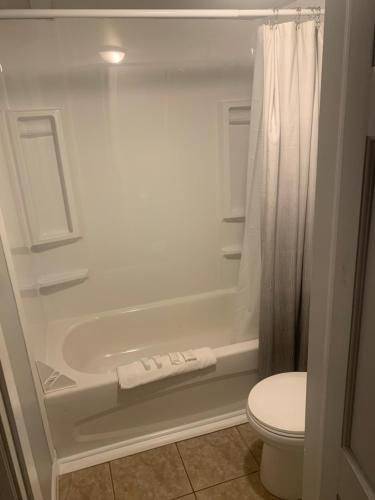 a bathroom with a white tub and a toilet at Skyline Motel in Fredericton