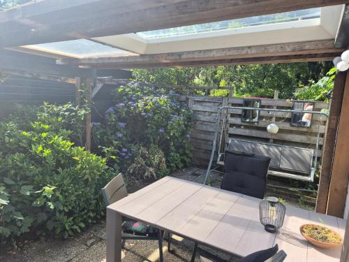 a patio with a table and chairs under a pergola at Chalet op de veluwe in Putten
