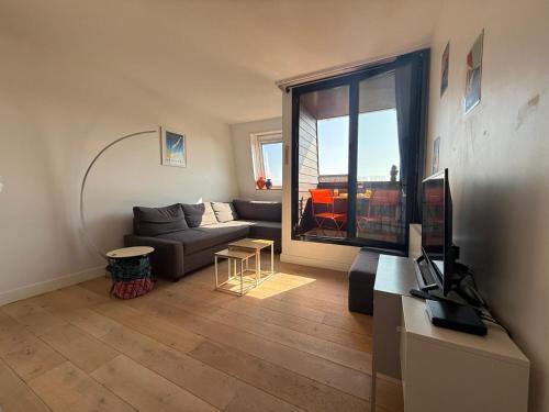 un salon avec un canapé et une grande fenêtre dans l'établissement Dans la Marina, charmant appartement, à Deauville