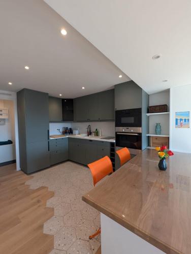 une grande cuisine avec une table et des chaises orange dans l'établissement Dans la Marina, charmant appartement, à Deauville
