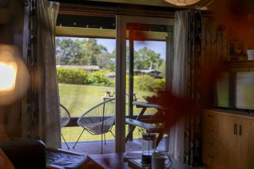 a room with a door open to a patio with a table and chairs at Woodside Lodge Cenarth in Cenarth