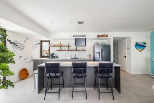 una cucina con isola e sgabelli da bar di Casa Orillia de Mar - The Wharf 5F a Willemstad